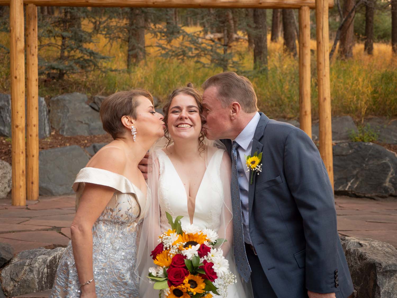 bride being kissed by mom and dad