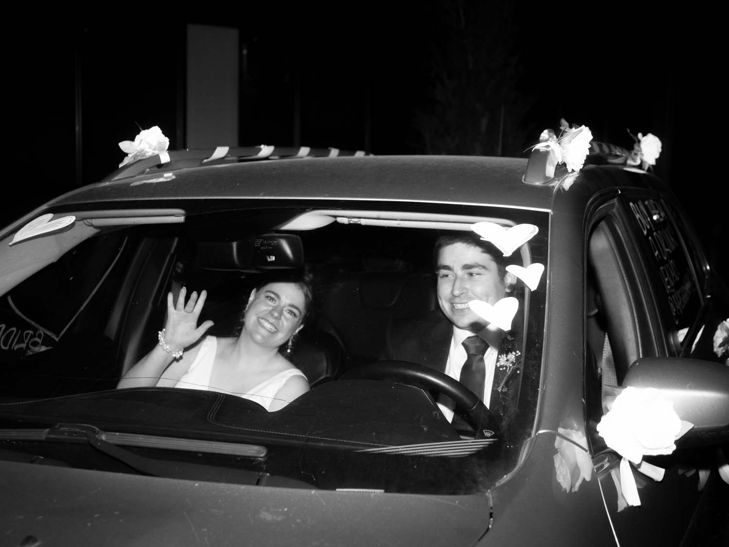 wedding couple in car driving away black and white